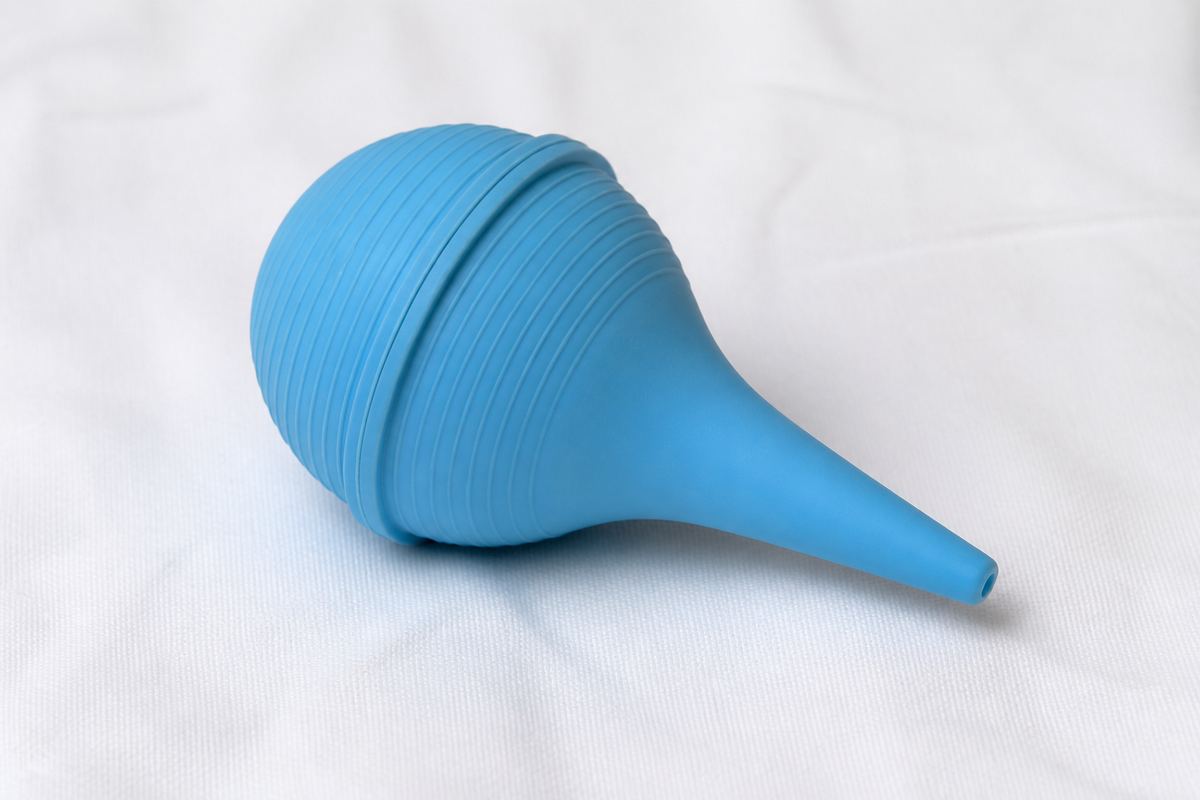Blue infant nasal bulb syringe on white linen.